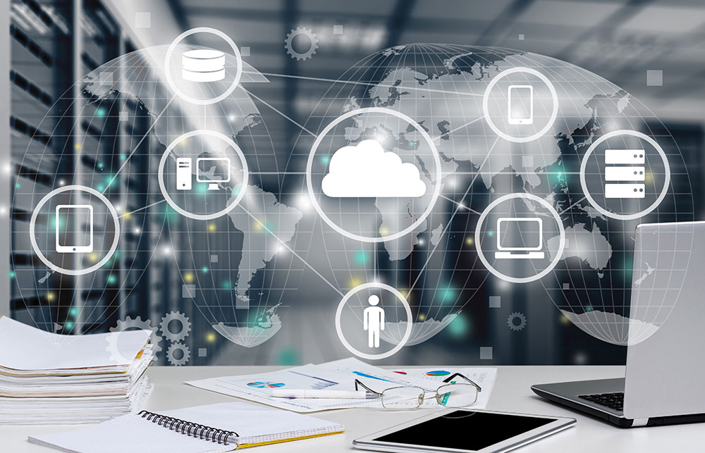 A workspace featuring a laptop and documents, overlaid with digital icons representing cloud computing, global networks, and various devices, set against a backdrop of server racks.